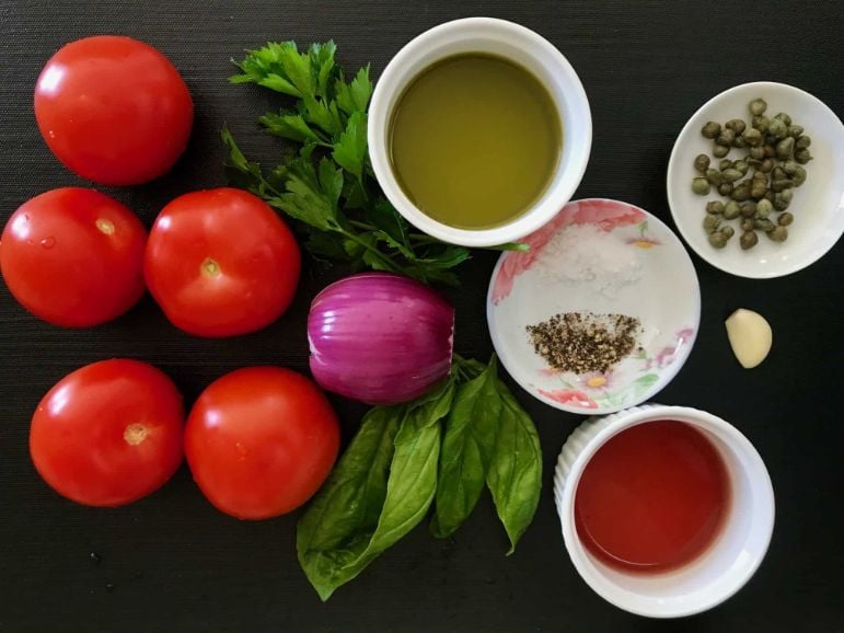 Black place mat with all of the ingredients for the Marinated Tomato Salad.