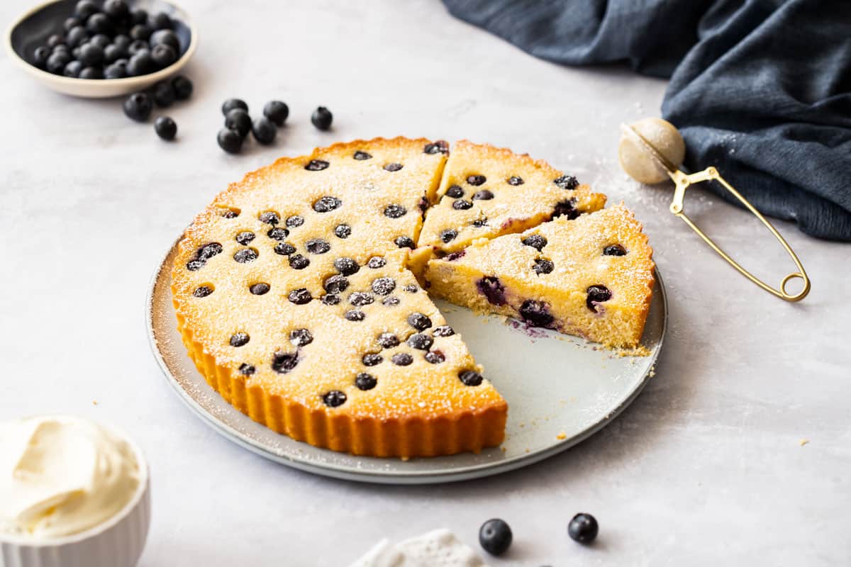 Blueberry Cake with one slice removed on grey platter.