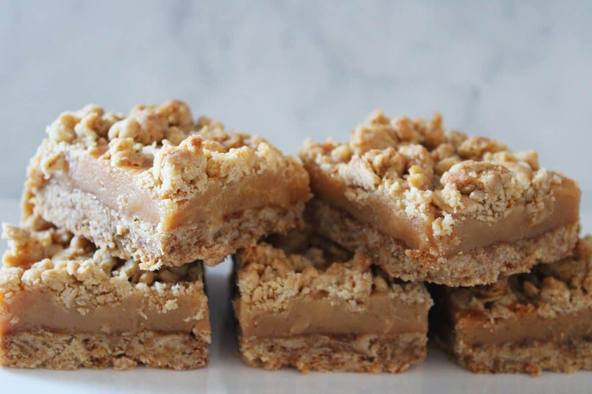 Five crumb bars stacked on a white plate.
