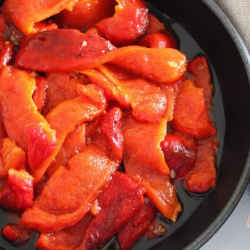 Black skillet with roasted peppers, with a beige napkin.