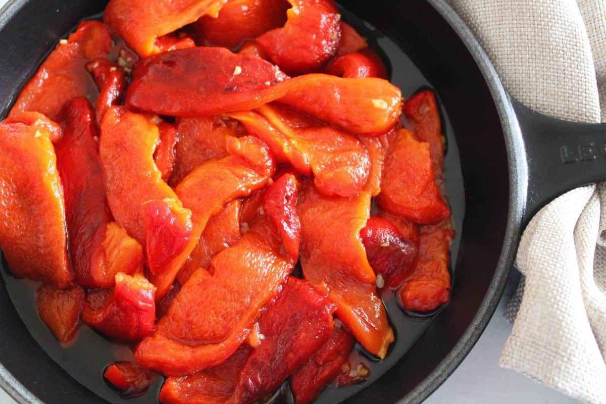 Black skillet with roasted peppers, with a beige napkin.
