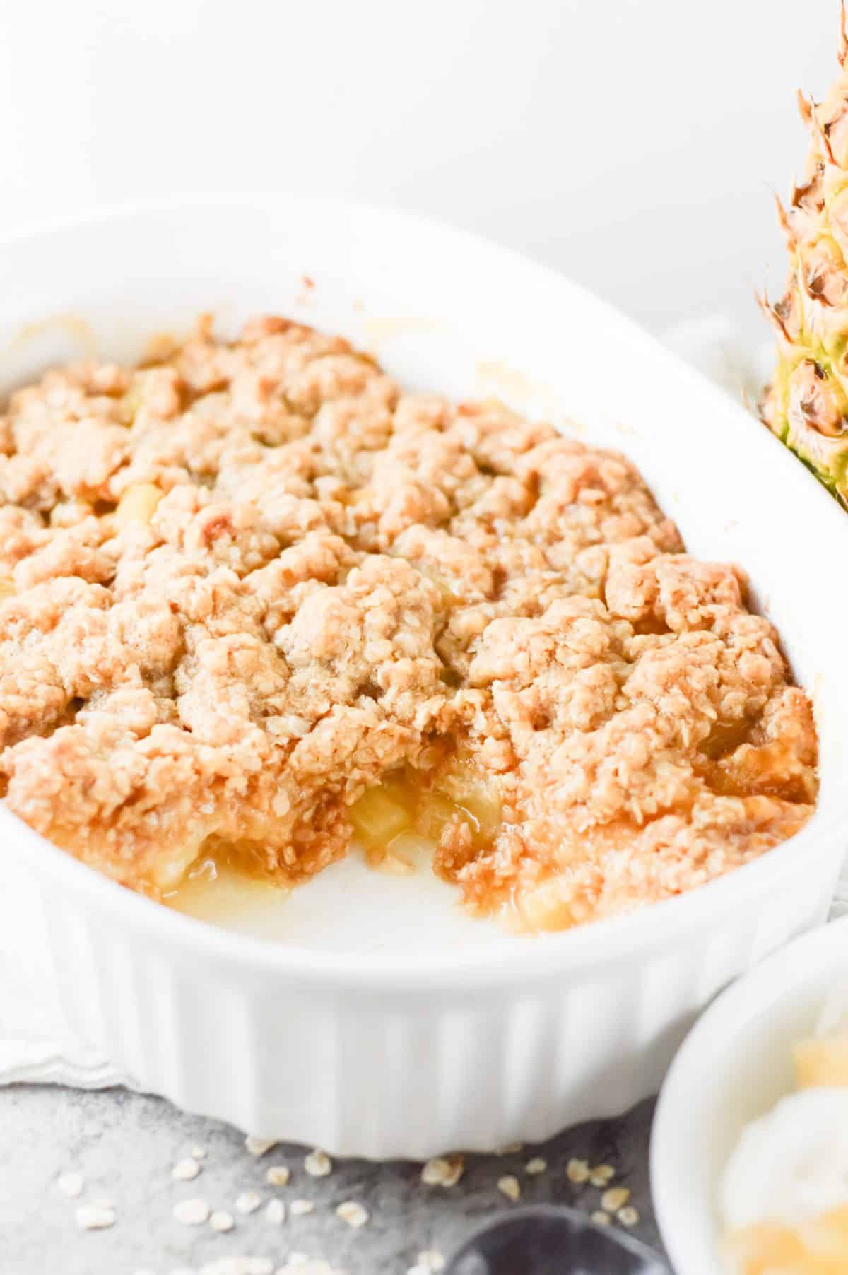 up close shot of pineapple crisp, baked in a white dish.