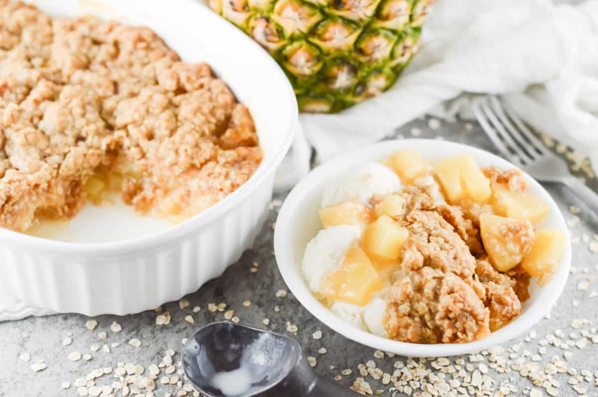 baking dish of pineapple crisp, with a bowl served on the right hand side.