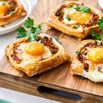 bacon and egg galettes on a wooden chopping board.