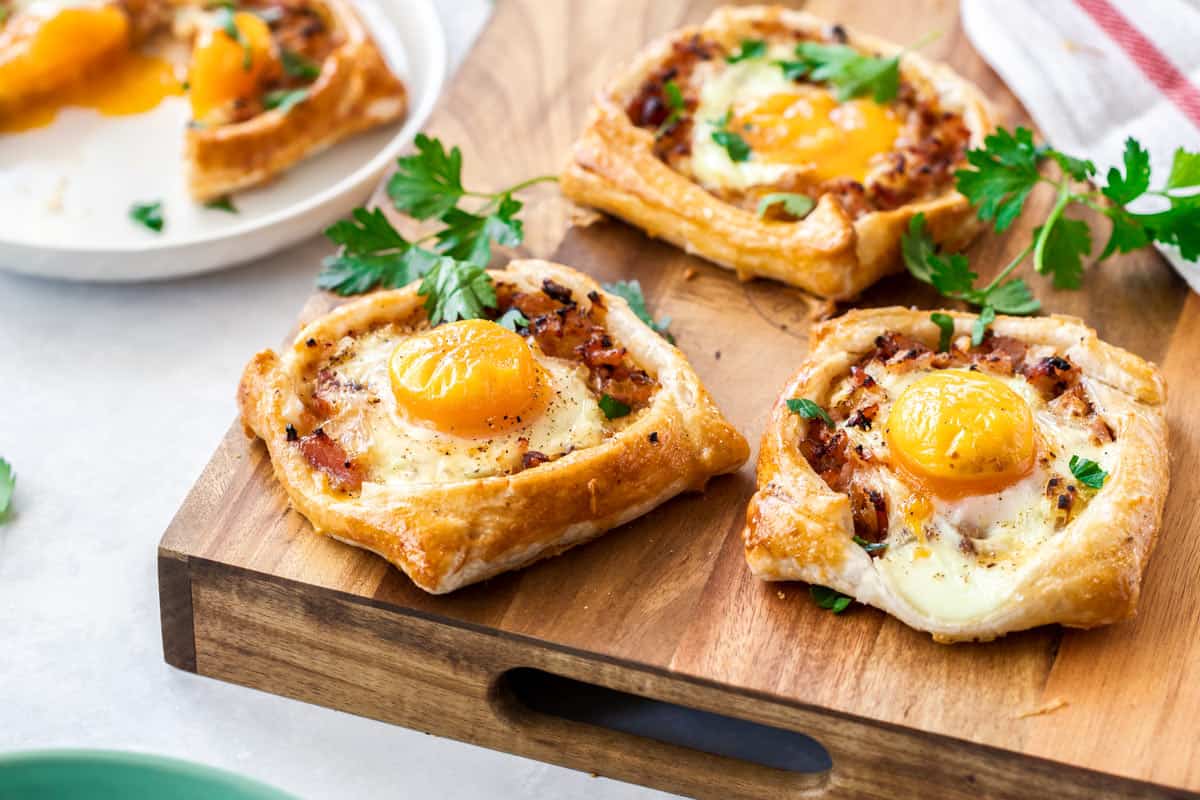 bacon and egg galettes on a wooden chopping board.