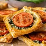 spinach galettes in a pile, on a wooden board, with a bowl of salad in the background.