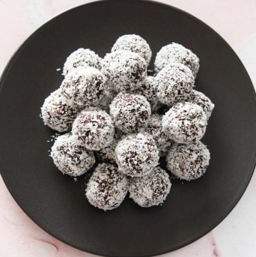 round black plate with bliss balls, sitting on a pink and white marble background.