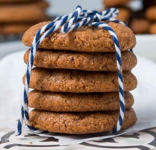 Stack of cookies, tied with a blue and white string, sitting on a white tile, with cookies in the background.