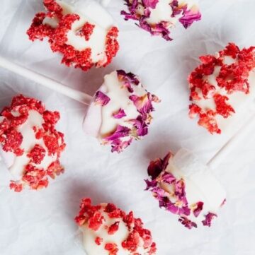 seven chocolate coated and decorated marshmallows lying down on parchment paper.
