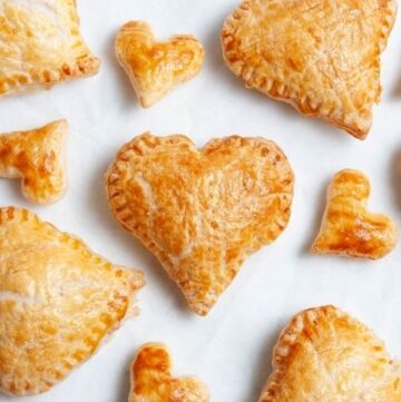 heart pastries and smaller heart pastries on a white baking sheet.