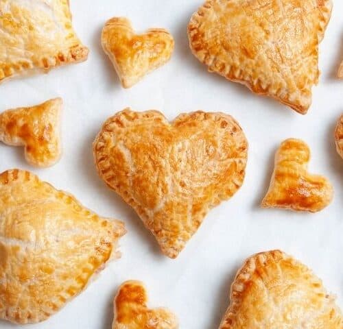 heart pastries and smaller heart pastries on a white baking sheet.
