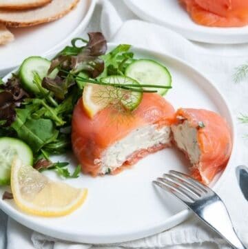 parcel cut in half, showing cream cheese filling, sitting on a plate with some salad and a wedge of lemon.