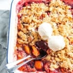 up close shot of crumble dish, with two spoons and two scoops of ice cream.