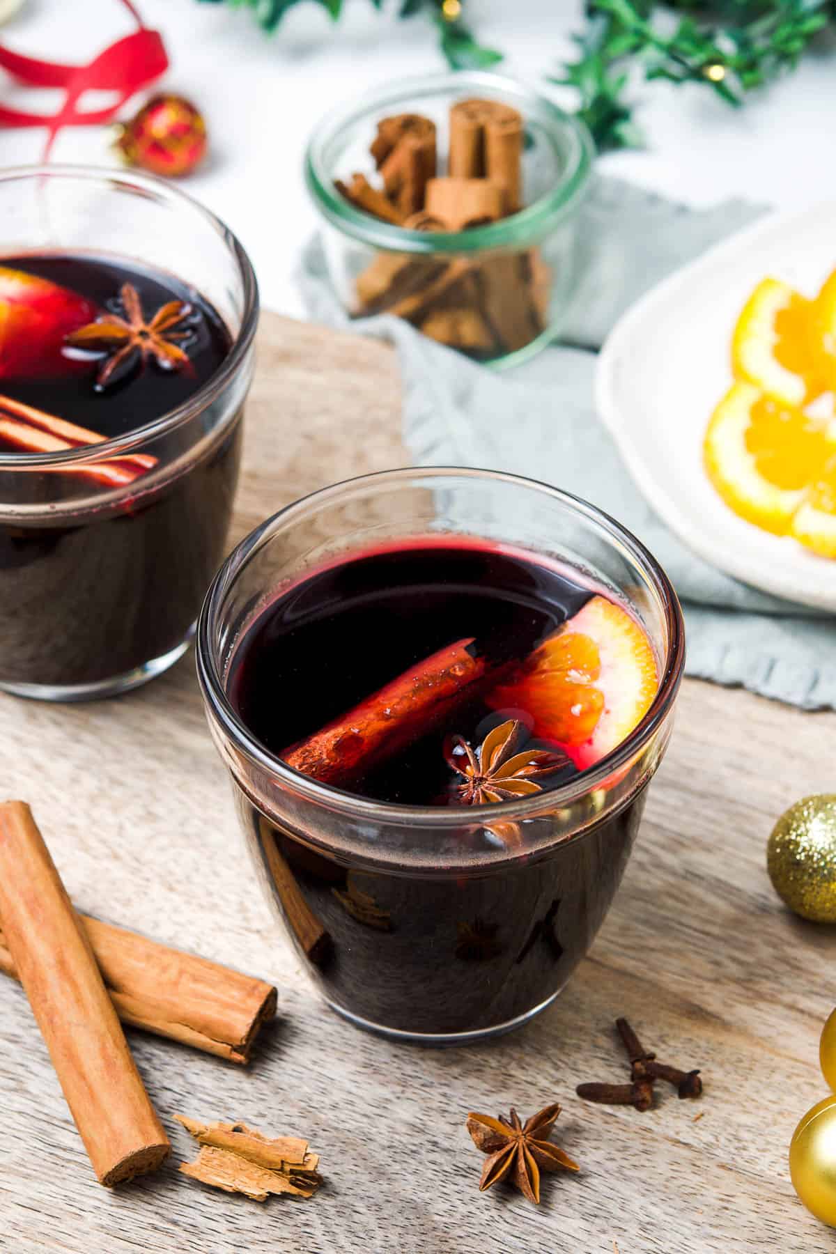 Two glasses with wine in it, with some cinnamon, star anise and orange.