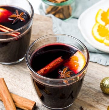 Two glasses with wine in it, with some cinnamon, star anise and orange.