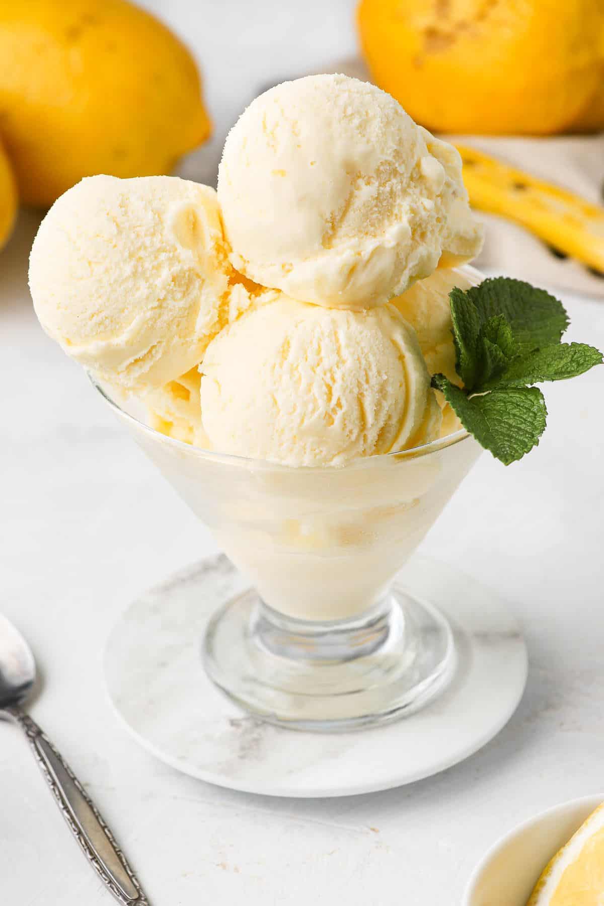 Scoops of ice cream in a glass dish, garnished with mint.