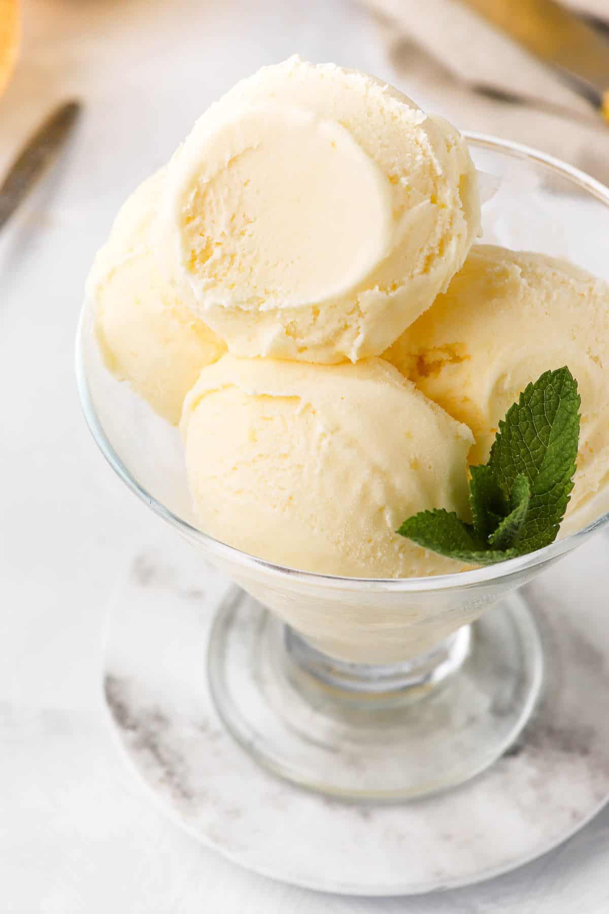 Scoops of ice cream in a glass dish, garnished with mint.