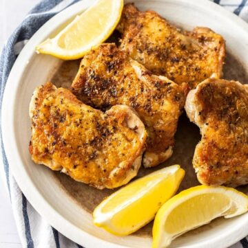 Dish of cooked thighs, with some lemon wedges around the edge.