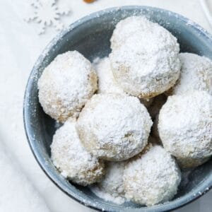 Round blue dish of cookies dusted with icing sugar.