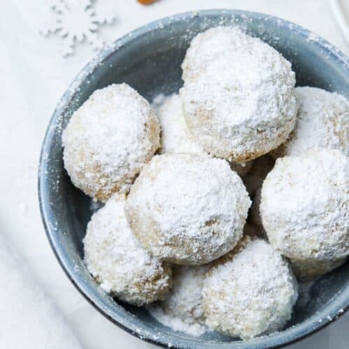 Round blue dish of cookies dusted with icing sugar.