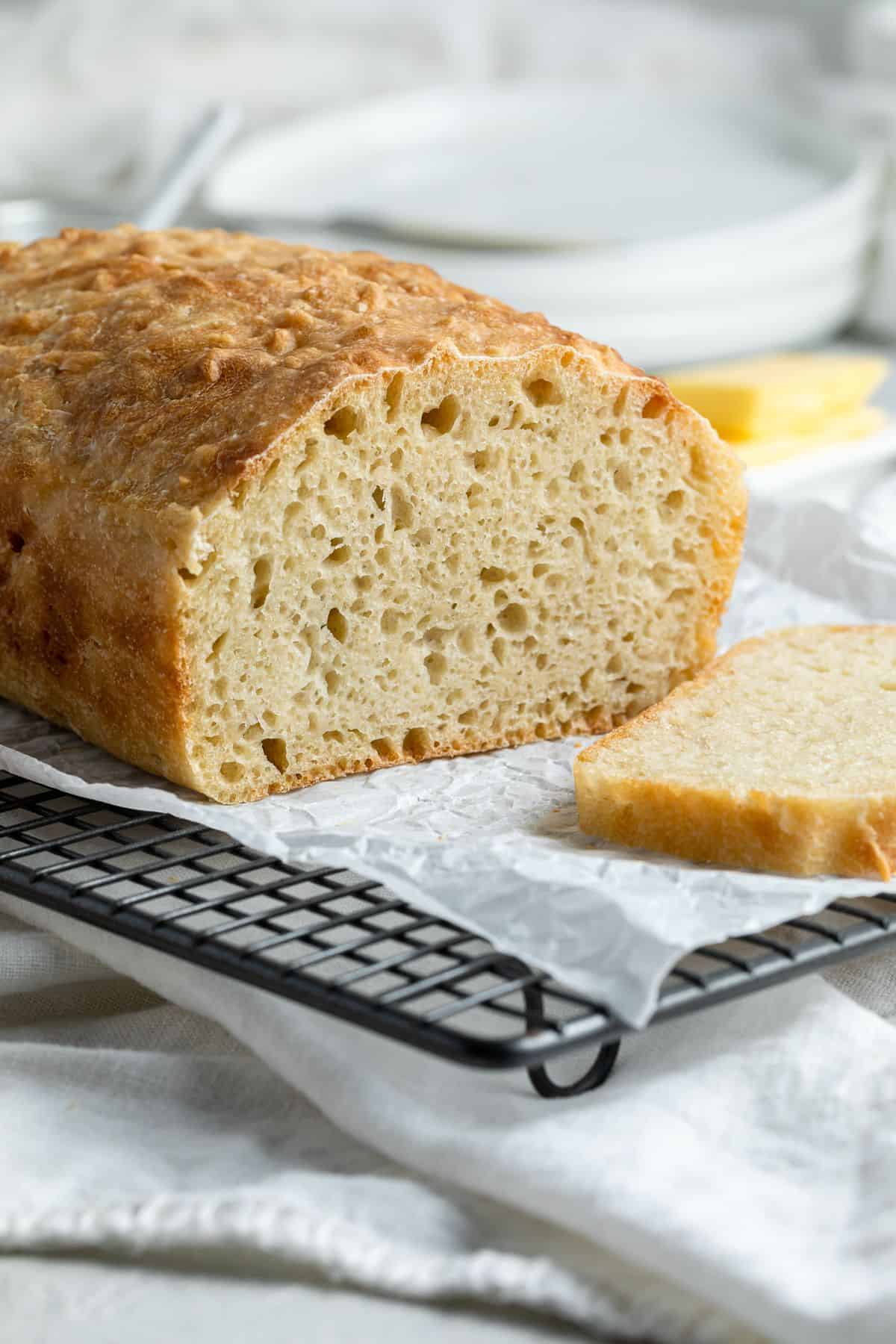 Cut loaf of bread sitting on rack.