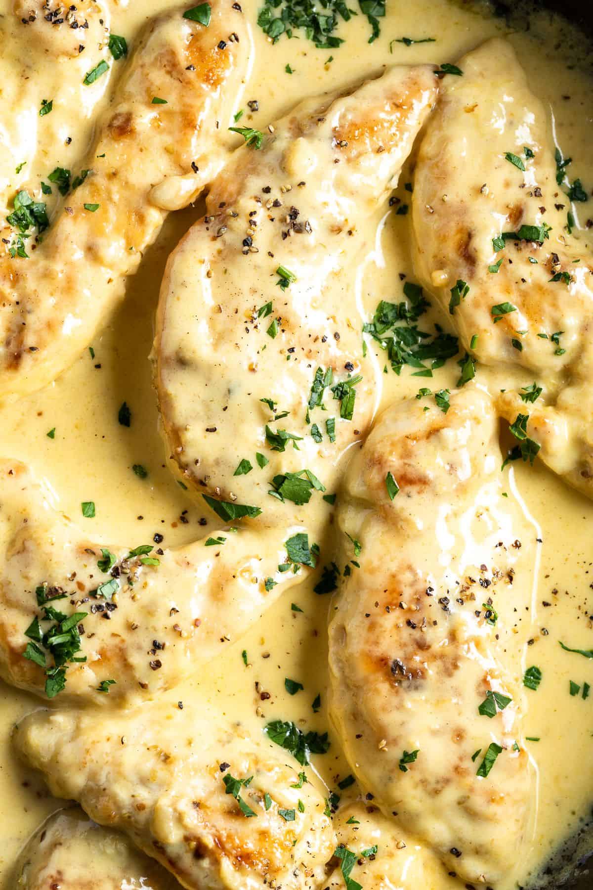 Up close shot of finished dish of chicken in cream sauce sprinkled with parsley.