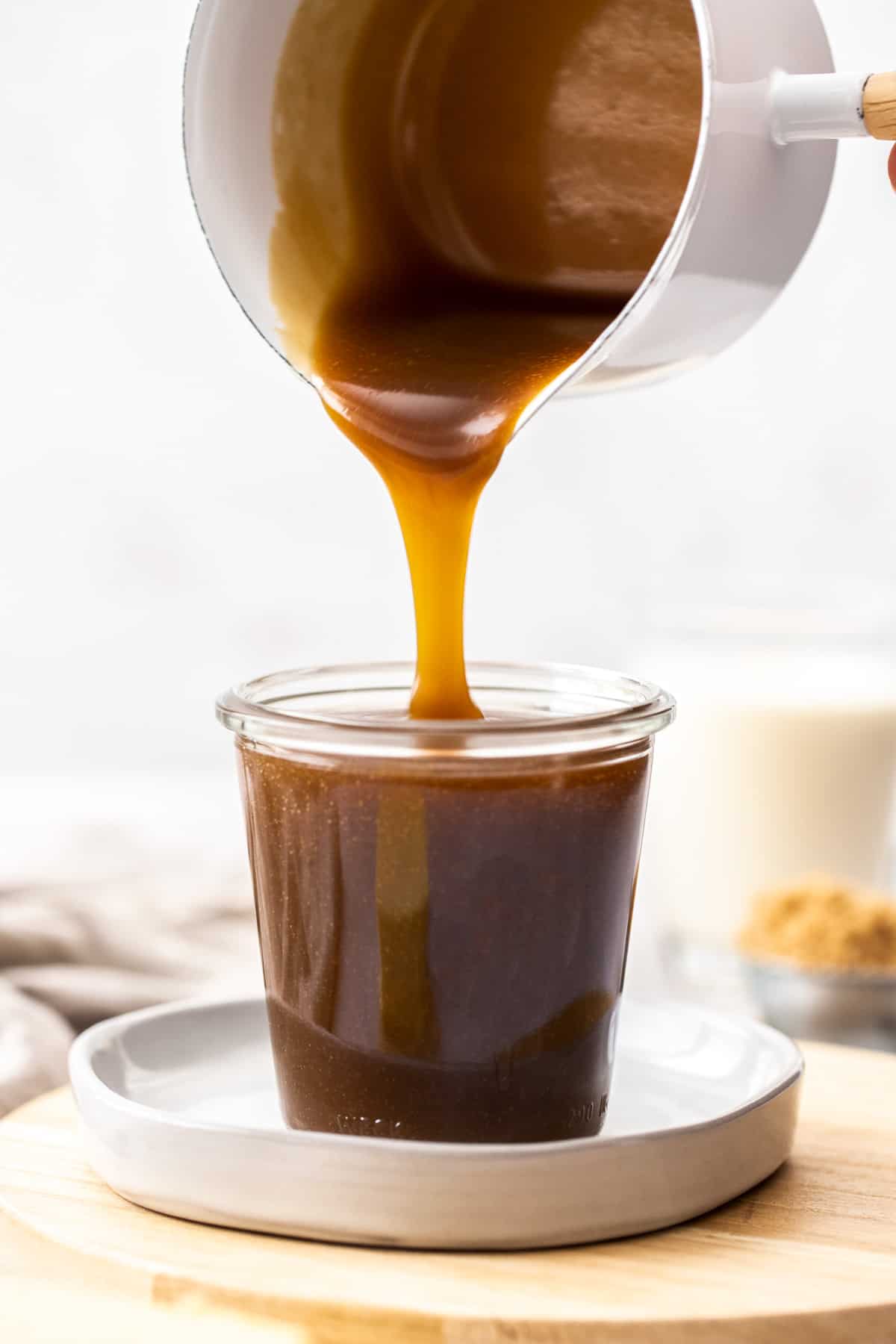 Pot of toffee sauce being poured into a glass jar.