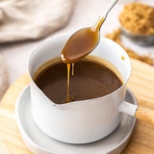 Small white pot of toffee sauce, with a spoon dipping into it.