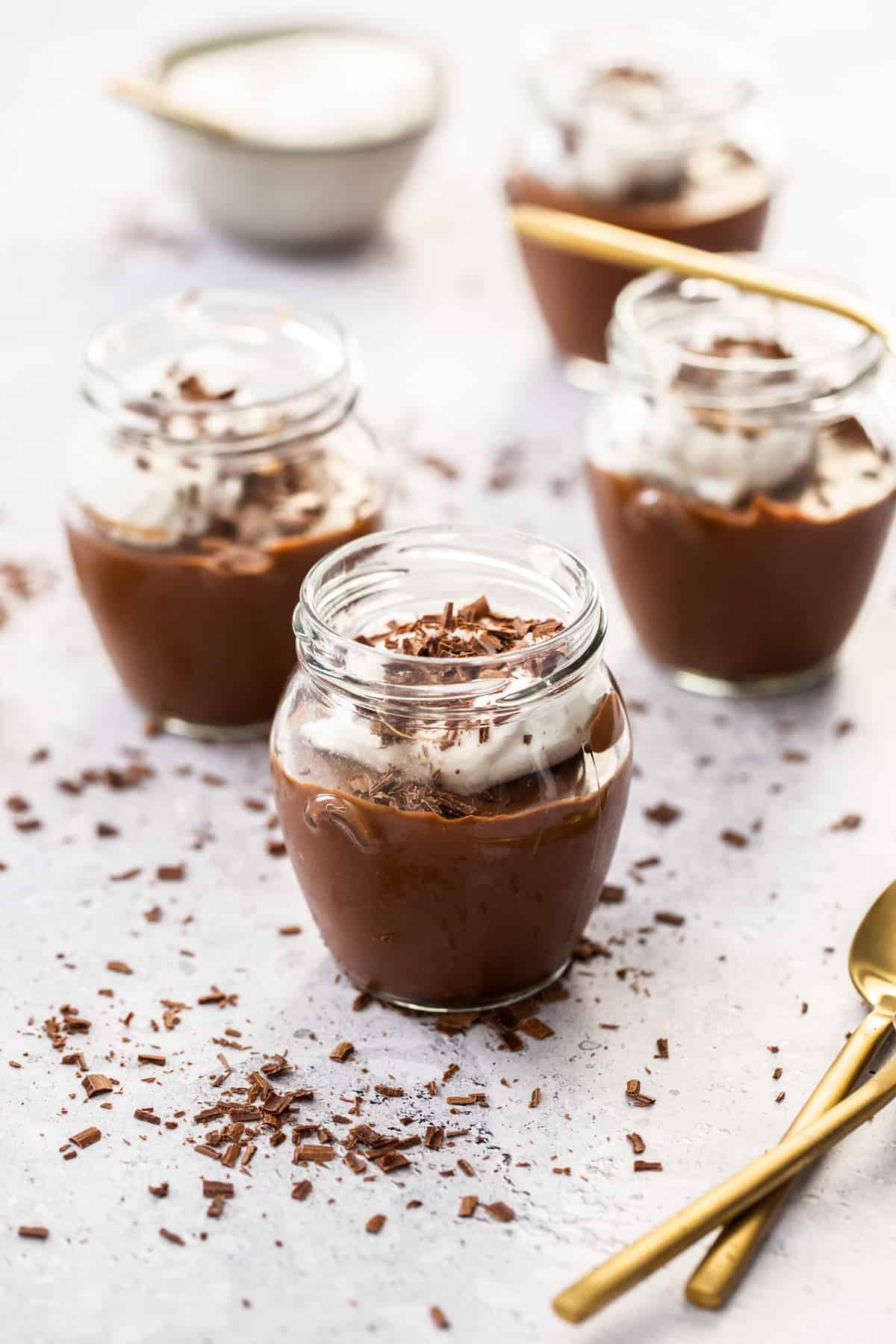 Three jars of mousse, with some gold spoons on the edge of photo.