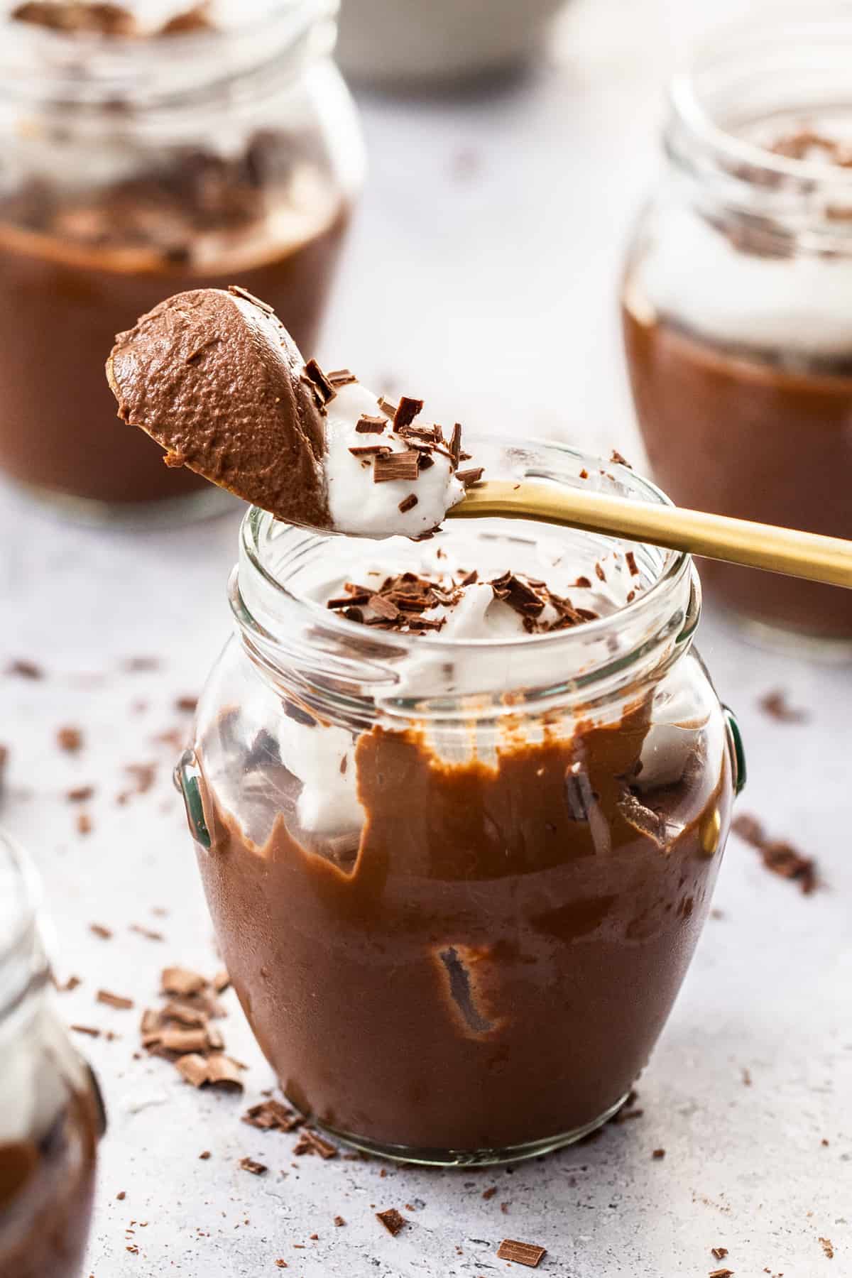 Jar of chocolate mousse, with a spoon resting on top with mousse on it.