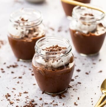 Three jars of mousse, with some gold spoons on the edge of photo.