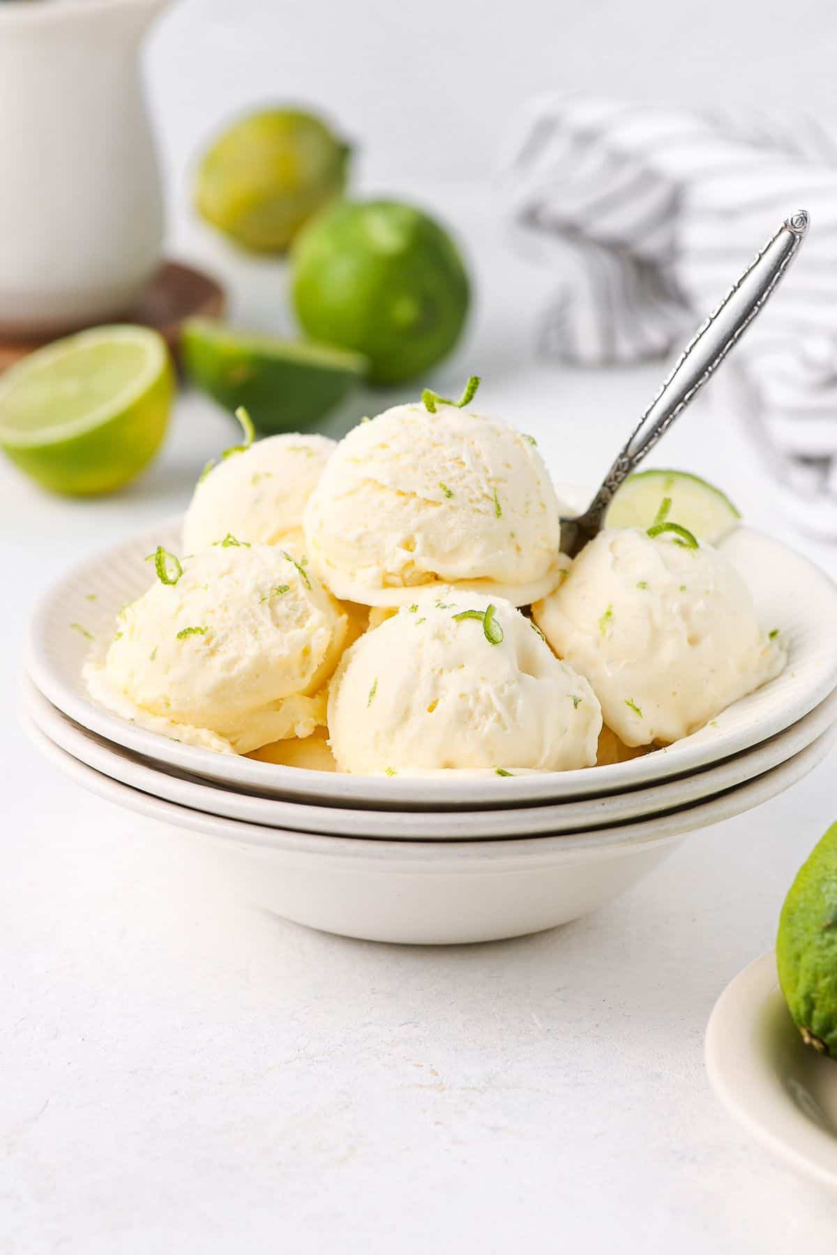 Bowl with several scoops of ice cream, garnished with lime zest, with a spoon sitting in it.