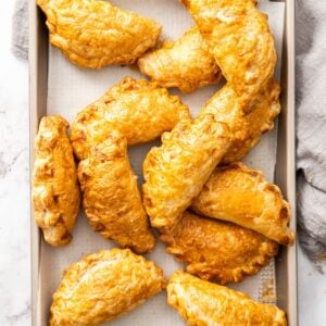 Tray of baked pasties, sitting on a grey cloth.