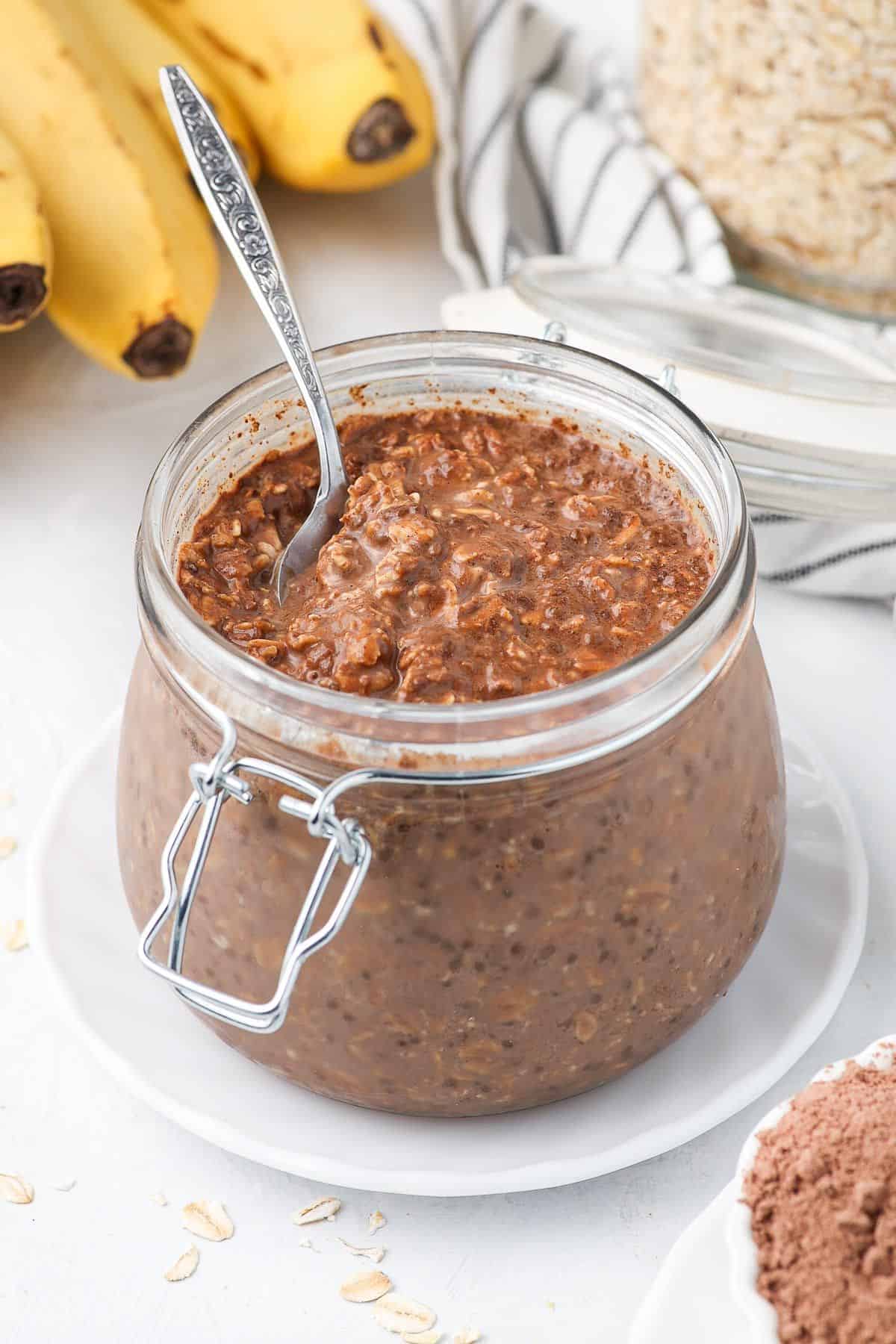 Jar of oats without any toppings, with a spoon in the jar.