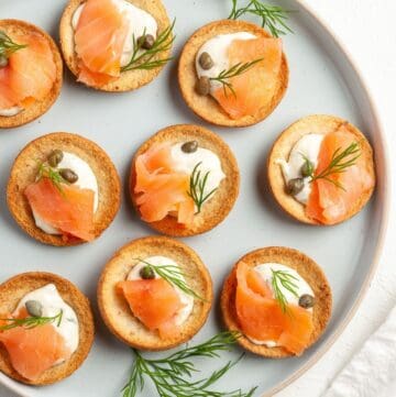 Round plate with canapés, garnished with some dill leaves.
