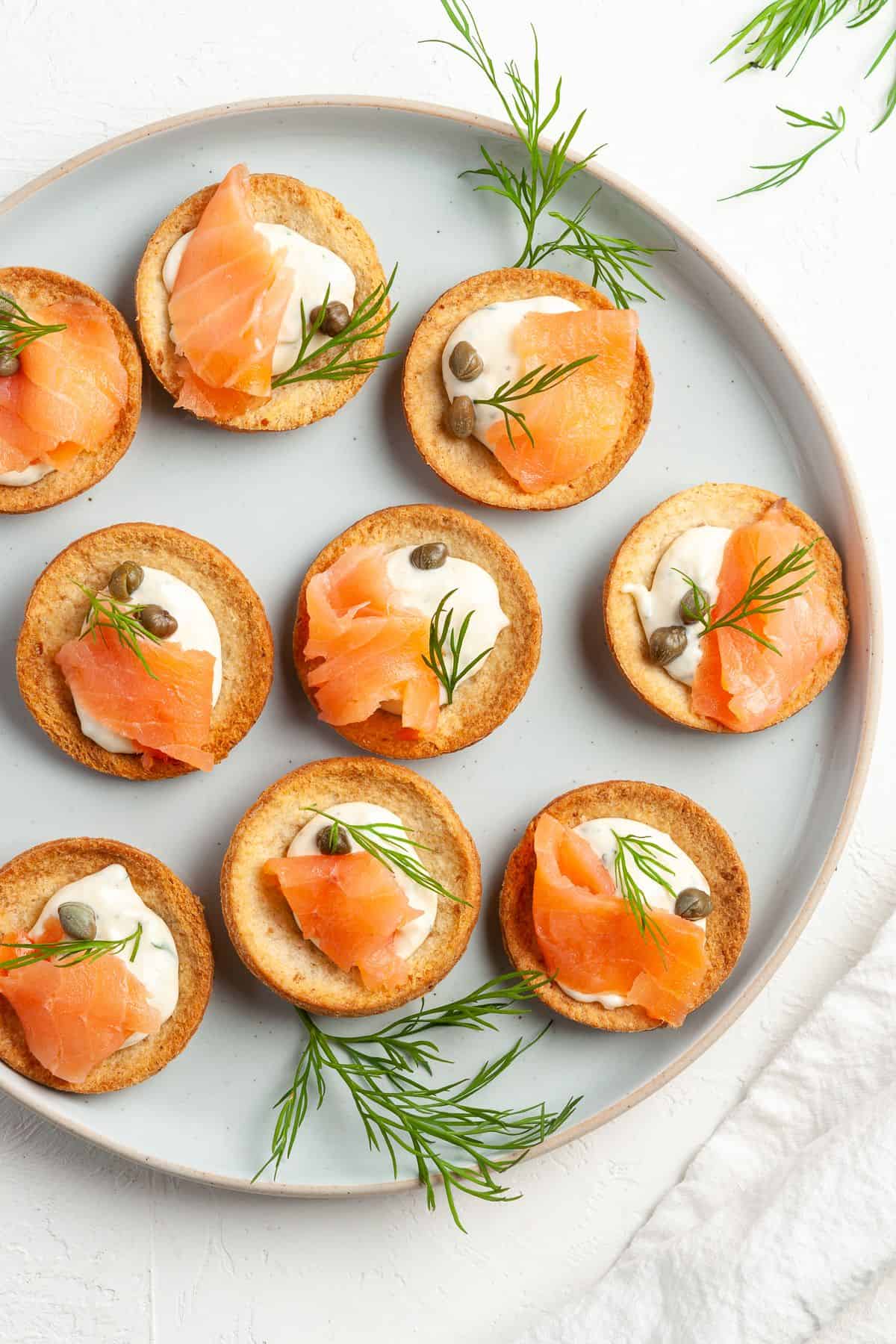 Round plate with canapés, garnished with some dill leaves.