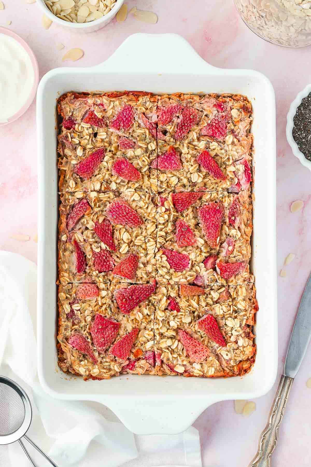White rectangular dish of baked strawberry oatmeal, cut into six pieces.