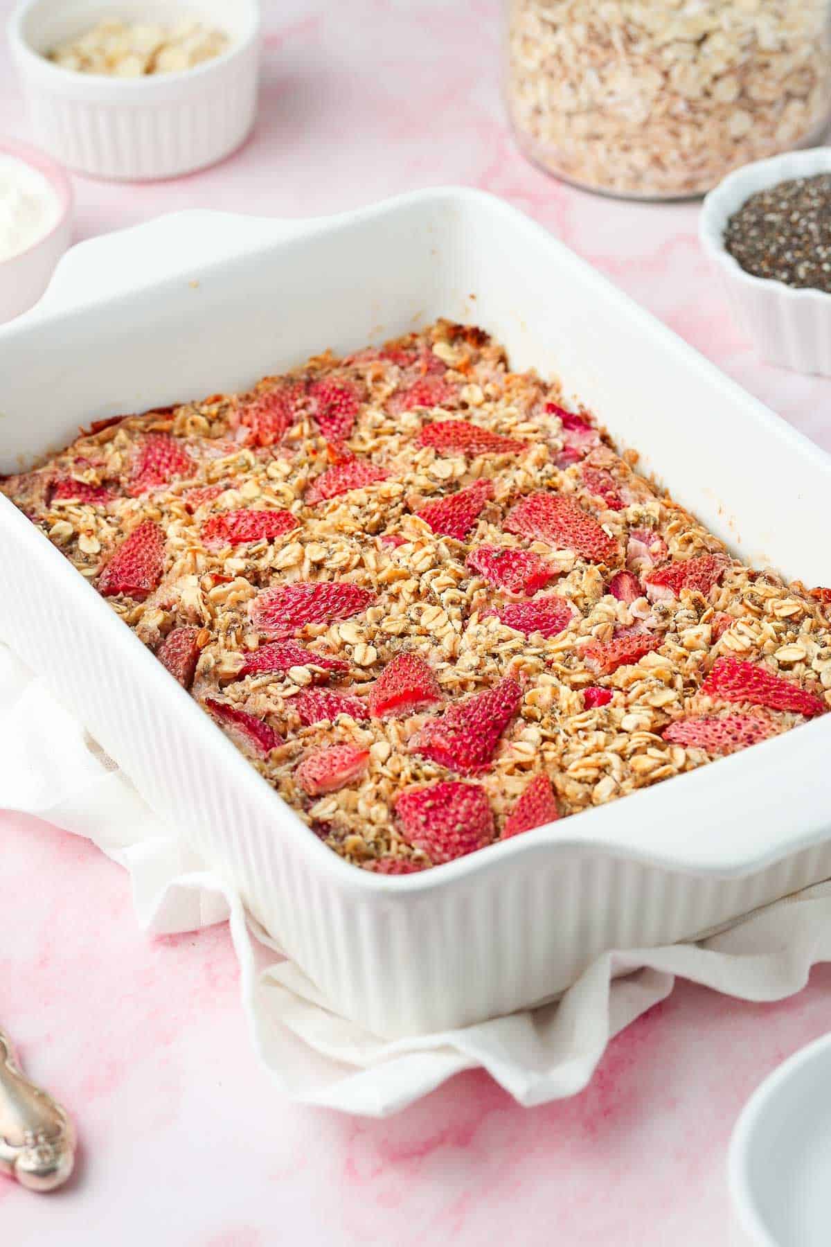 White rectangular dish of baked strawberry oatmeal, cut into six pieces.