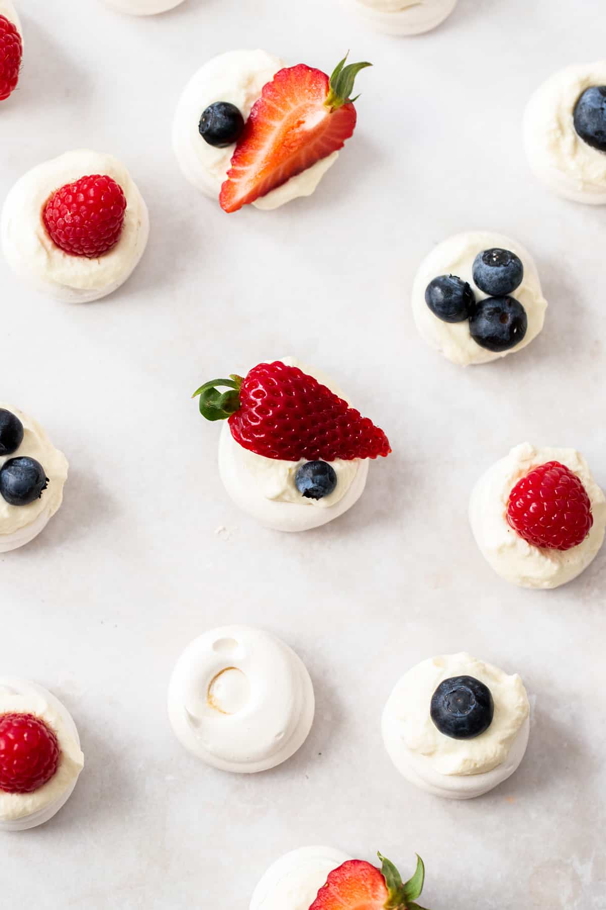 Overhead shot of mini meringue nests filled with cream and berries.