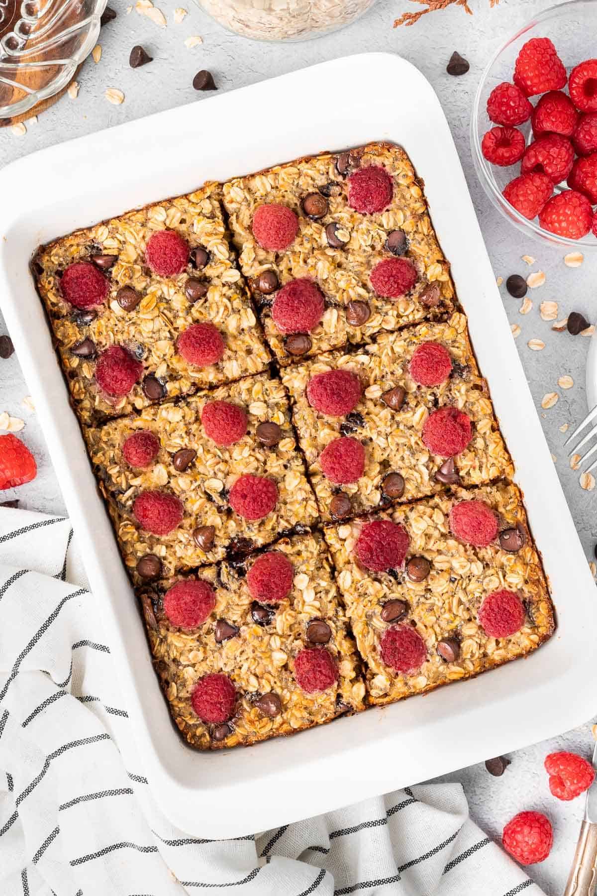White rectangular dish of baked raspberry oatmeal, cut into six pieces.