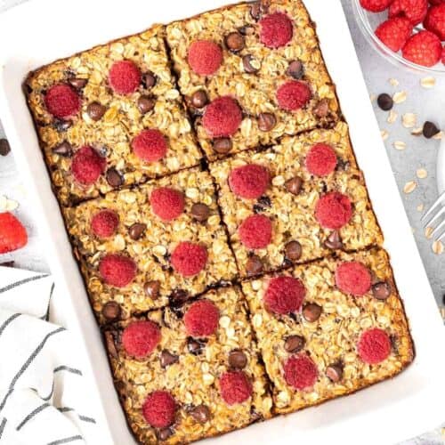 White rectangular dish of baked raspberry oatmeal, cut into six pieces.