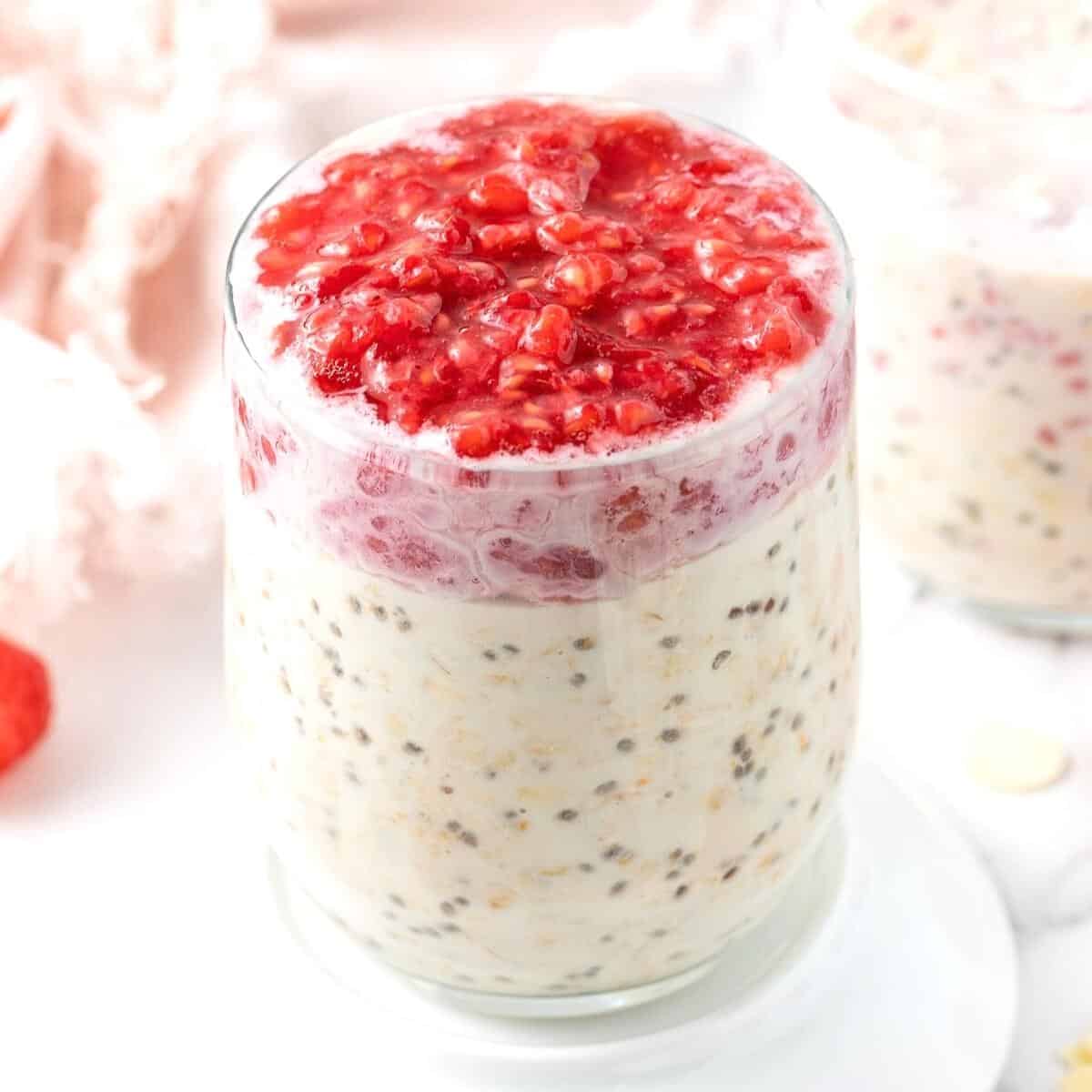 Glass jar of overnight oats, topped with crushed raspberries.