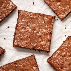 Overhead shot of cut squares of brownies on parchment paper.