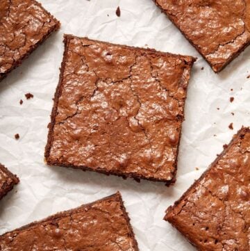 Overhead shot of cut squares of brownies on parchment paper.