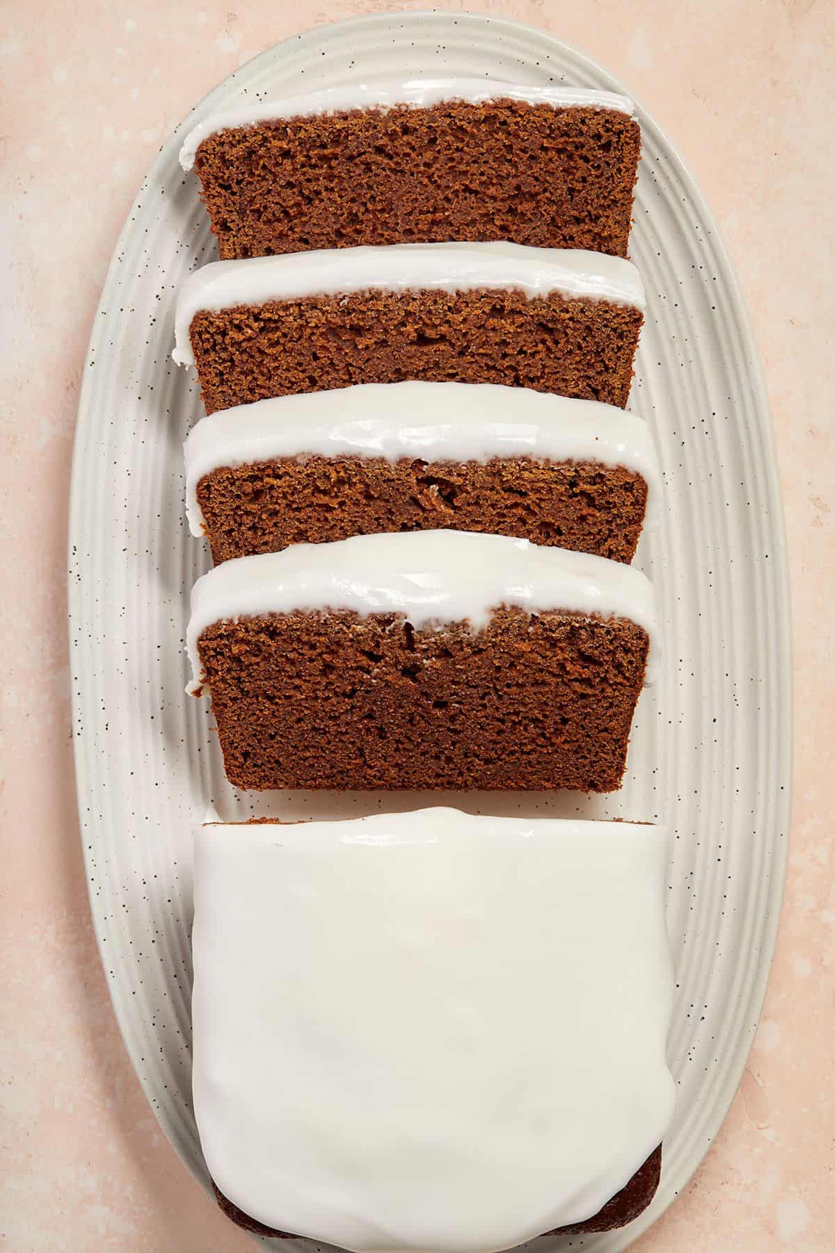 Slices of gingerbread loaf and half a loaf, sitting on a white oval dish.