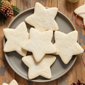 Round grey plate with five shortbread cookies, and some decorations around the edge of the photo.
