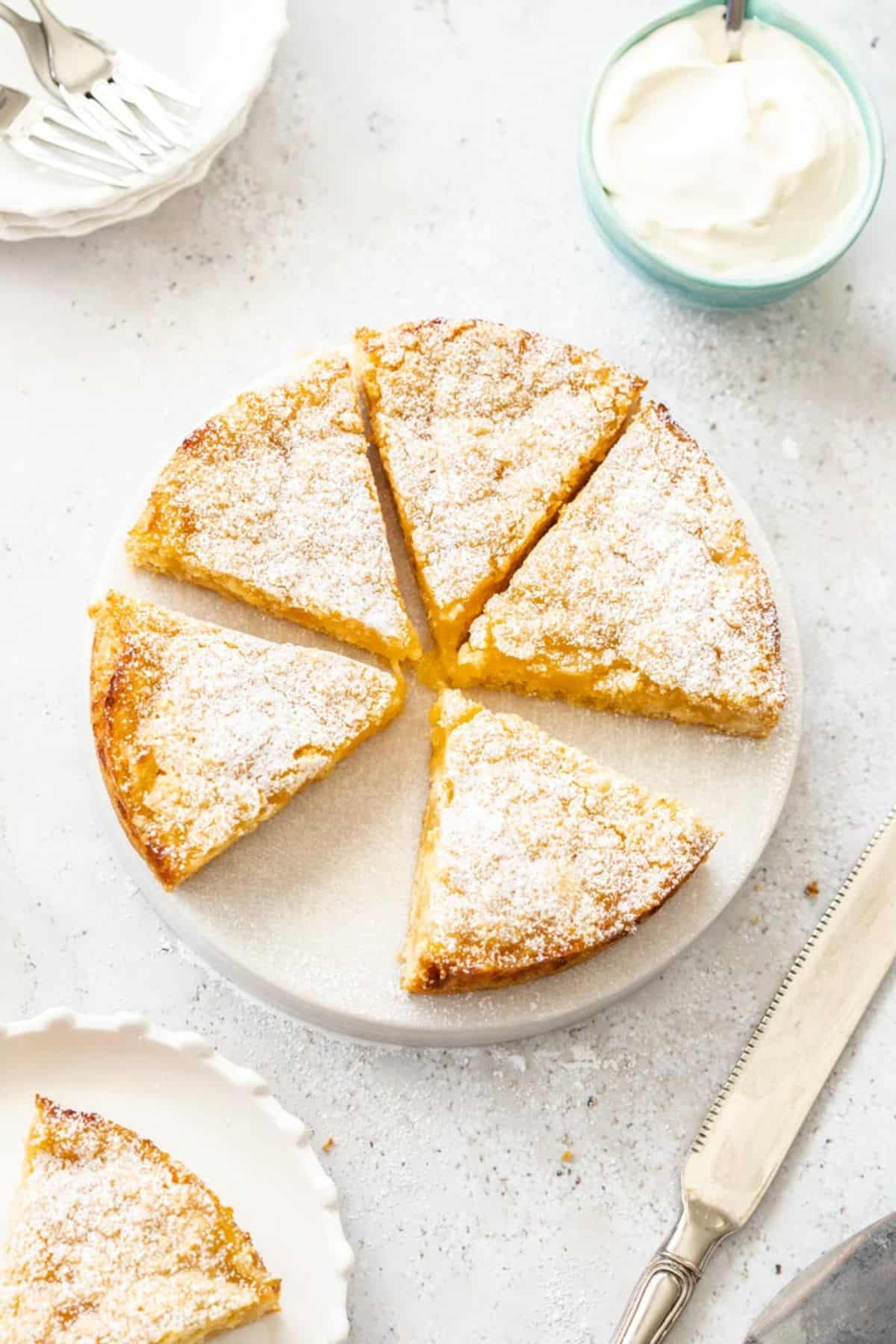 Overhead shot of Lemon Curd Cake, with a slice missing, sitting on a round white dish.
