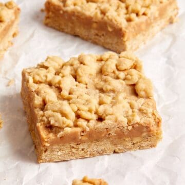 Cut squares of Peanut Butter Oatmeal Bars, sitting on some baking paper.