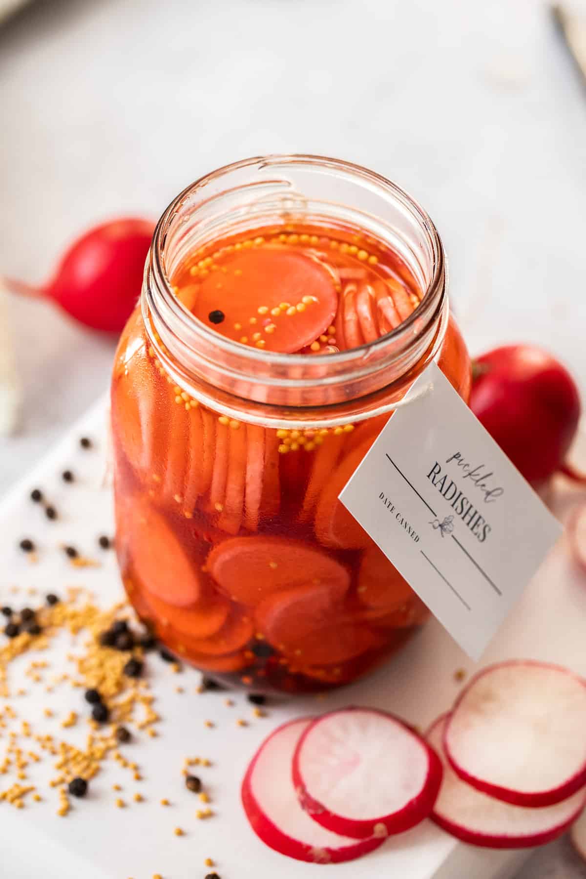 Glass jar of Pickled Radishes, with a label around the neck of the jar.