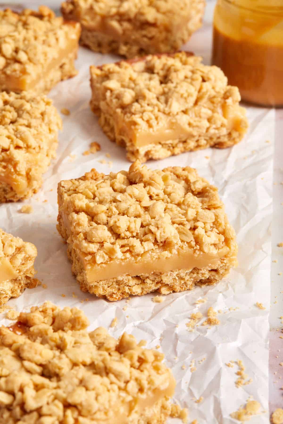 Cut squares of Caramel Oatmeal Bars, on a piece of baking paper.